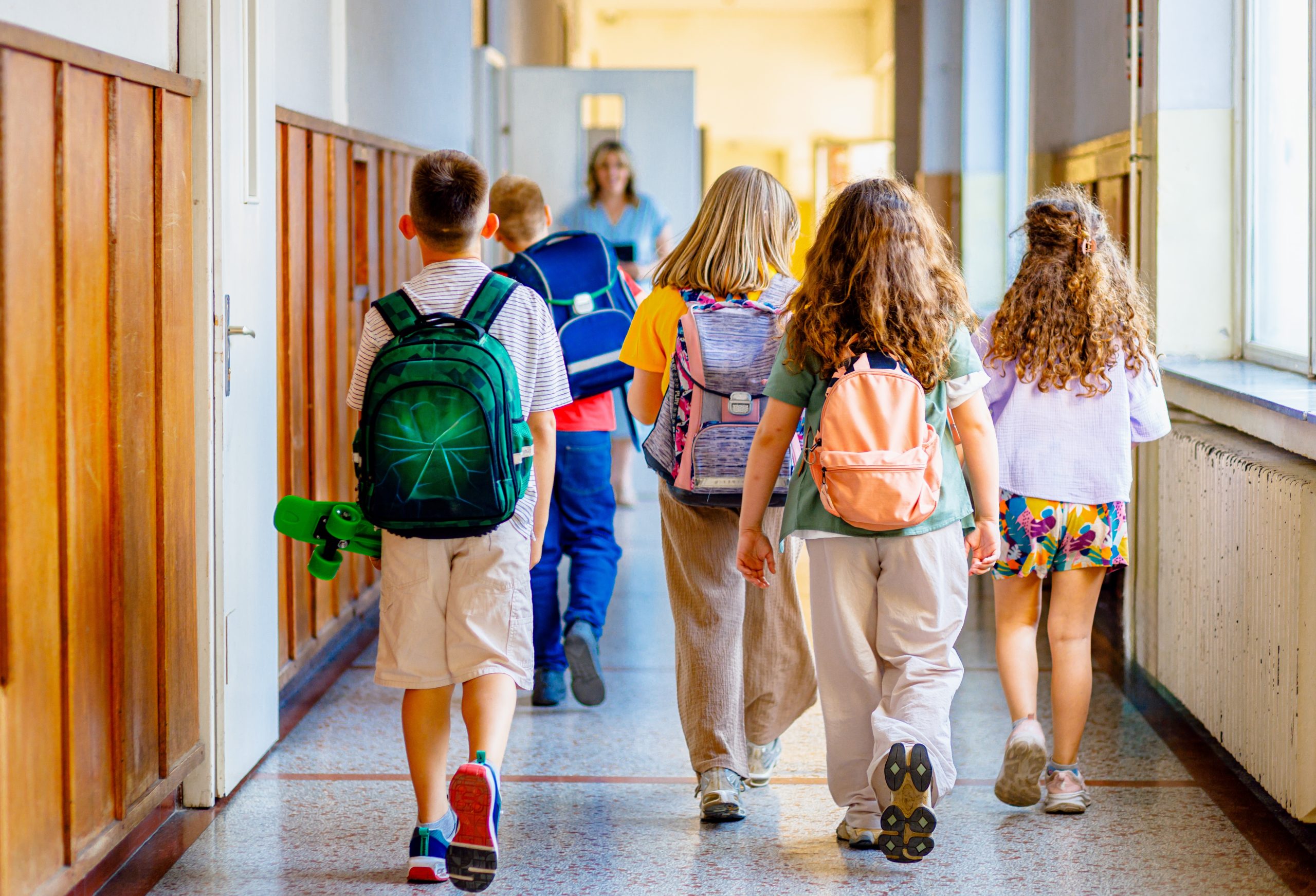 Rear,View,Of,Schoolkids,Walking,On,School,Hallway,Approaching,The